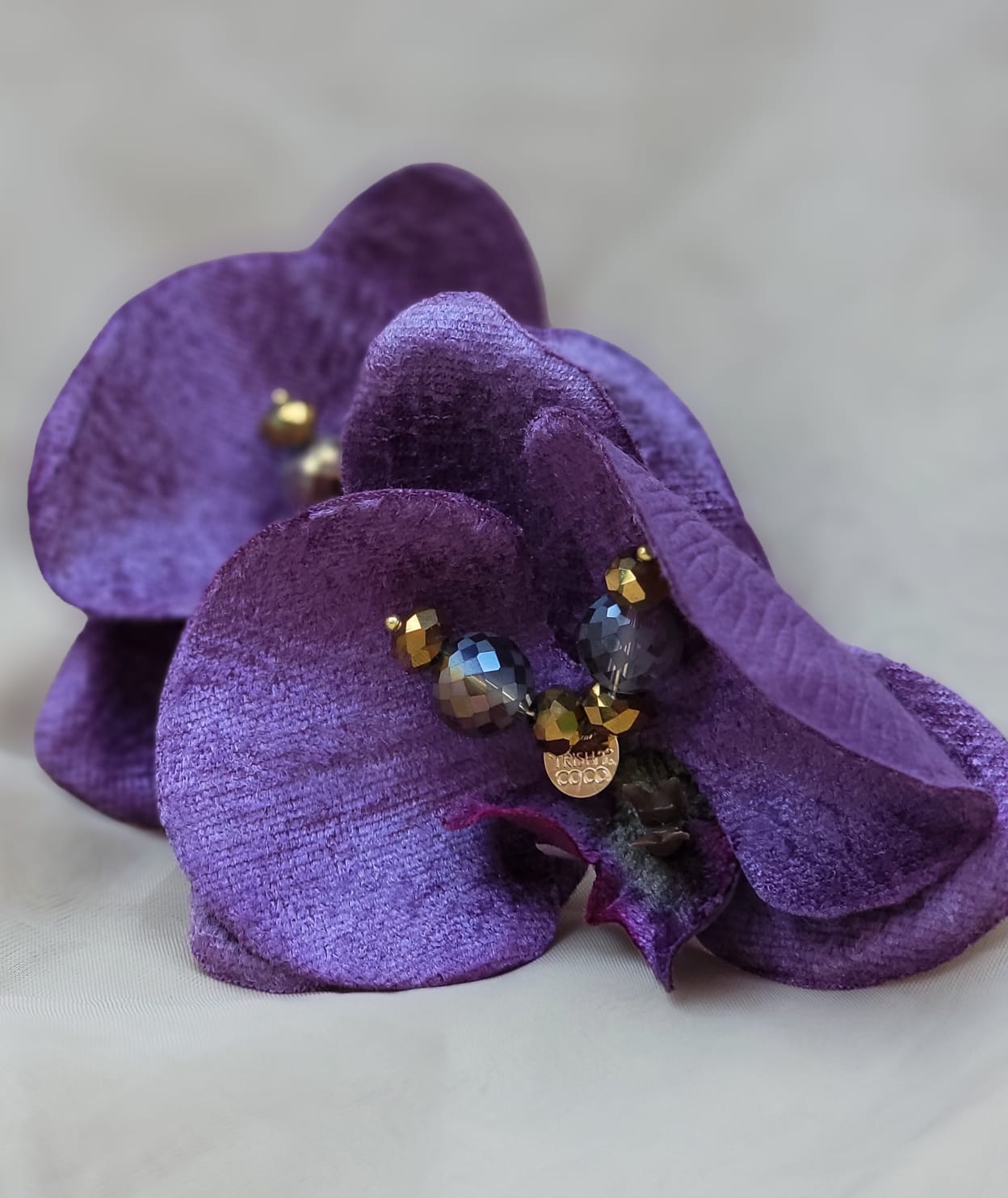 Descubre las Orquídea Nocturna de Trish T CoCo: pantallas florales hechas a mano con terciopelo violeta y cristales dorados. Inspiradas en el lujo tropical y el poder femenino.
